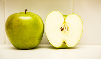 Whole and Half Green Apple on Countertop