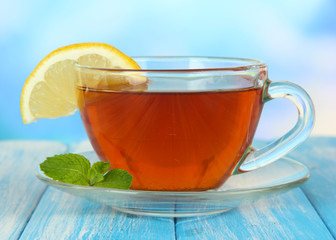 Cup of tea with lemon on table on blue background