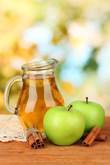 Full jug of apple juice and apple