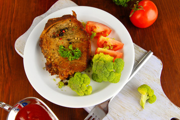 Piece of fried meat on plate on wooden table close-up