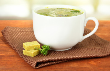Cup of soup with bouillon cubes on wooden table
