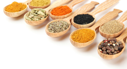Assortment of spices in wooden spoons, isolated on white