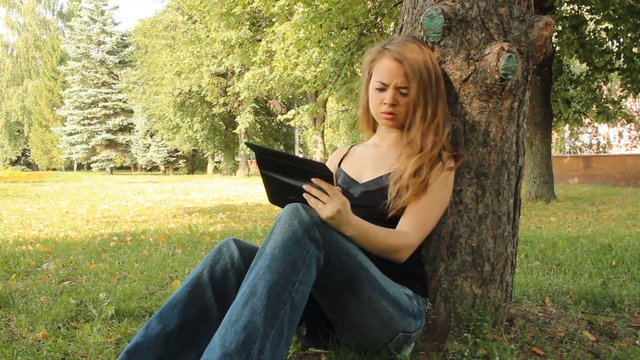 A young girl in a park with a tablet computer. summer  