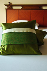 White Bed with two green decorated Pillows