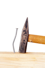 Crooked nail in the wooden board with a hammer