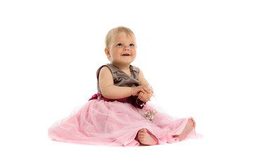 Adorable little baby girl in pink dress sitting on floor