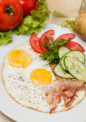 Fototapeta na wymiar bacon and eggs with garnish on white plate