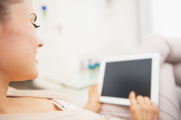 Young woman laying on couch with tablet pc . rear view