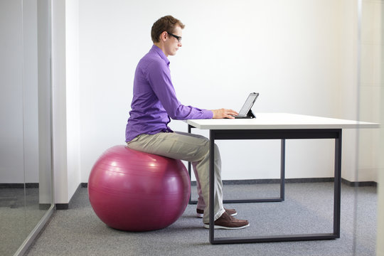 man on stability ball  with tablet - correct sitting position