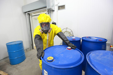 risky job - worker in  uniform at barrels with toxic waste