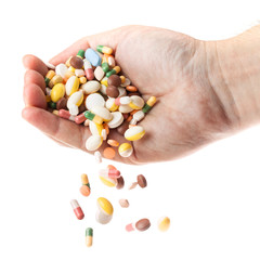 Man's hand holding and dropping a handful of medicine pills 