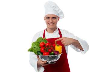 Young chef holding vegetables bowl