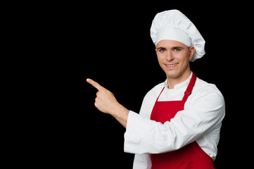 Young chef pointing towards something