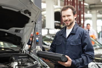 Fototapeta na wymiar Cheerful mechanic. Young cheerful mechanic standing near the car