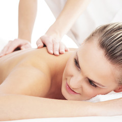 Obraz na płótnie Canvas A young blond woman on a back massage procedure