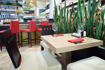 Square table with glasses and bar in hall of Japanese restaurant