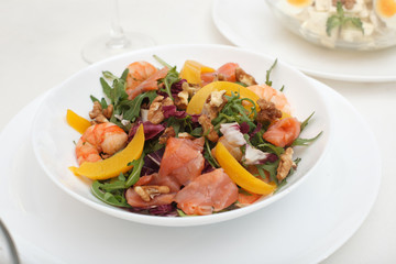 Fresh mixed salad with nuts, shrimps, salmon and peaches close