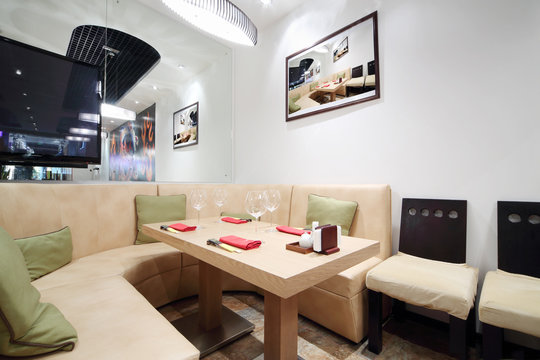 Wooden table, beige leather sofa and mirror in cozy restaurant