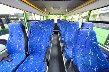 Blue seats for passengers in saloon of empty city bus
