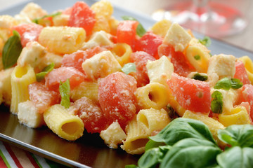 Piatto di pasta fredda con mozzarella, pomodori e basilico