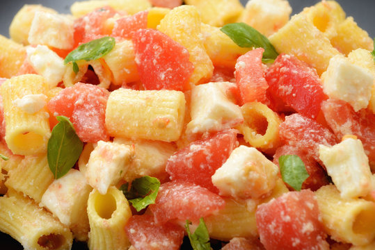 Piatto di pasta fredda con mozzarella, pomodori e basilico