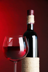 Glass of wine with bottle on bright red background