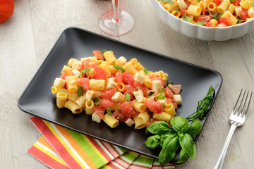 Piatto di pasta fredda con mozzarella, pomodori e basilico