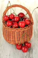 Cherry berries in wicker basket on wooden table close up