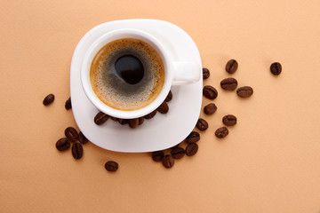 Cup of coffee with coffee beans on beige background