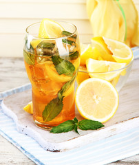 Iced tea with lemon and mint on wooden table