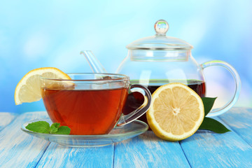 Cup of tea with lemon on table on blue background