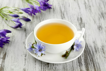 Cup of tea with chicory, on wooden background