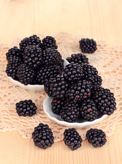 Sweet blackberry in bowls on wooden table