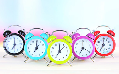 Colorful alarm clocks on table on light background