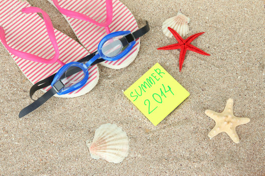 Composition with flip flops, goggles on sand background