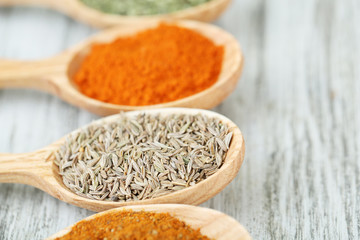 Assortment of spices in wooden spoons on wooden background
