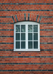 Fototapeta na wymiar White painted wood arched window in a red brick wall