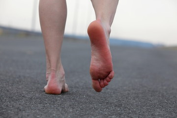 Closeup of man's bare feet walking away on the road