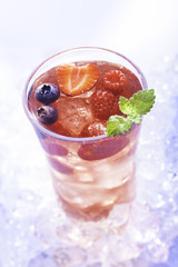 cold refreshment with .berries, mint and soda on ice cubes.