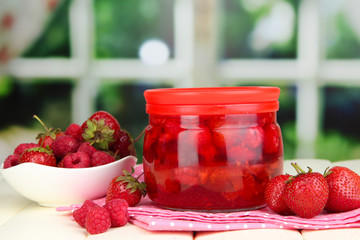 Home made berry jam on wooden table on window background