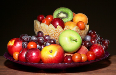 Assortment of juicy fruits on wooden table, on  dark background