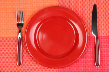 Knife, color plate and fork, on color background