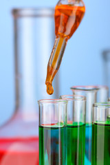 Laboratory pipette with drop of color liquid over glass test