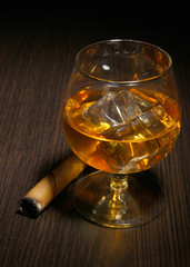 Brandy glass with ice on wooden background