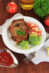 Piece of fried meat on plate on wooden table close-up