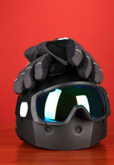 Winter sport glasses, helmet and gloves, on red background
