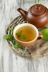 Teapot and cup of herbal tea with fresh mint on wooden table
