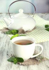 Teapot and cup of herbal tea with fresh mint flowers