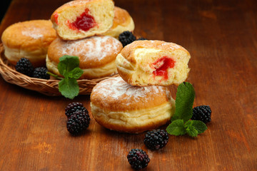 Tasty donuts with berries on wooden table