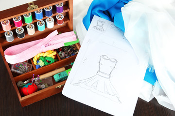 Sewing kit in wooden box,cloth and sketch on wooden table